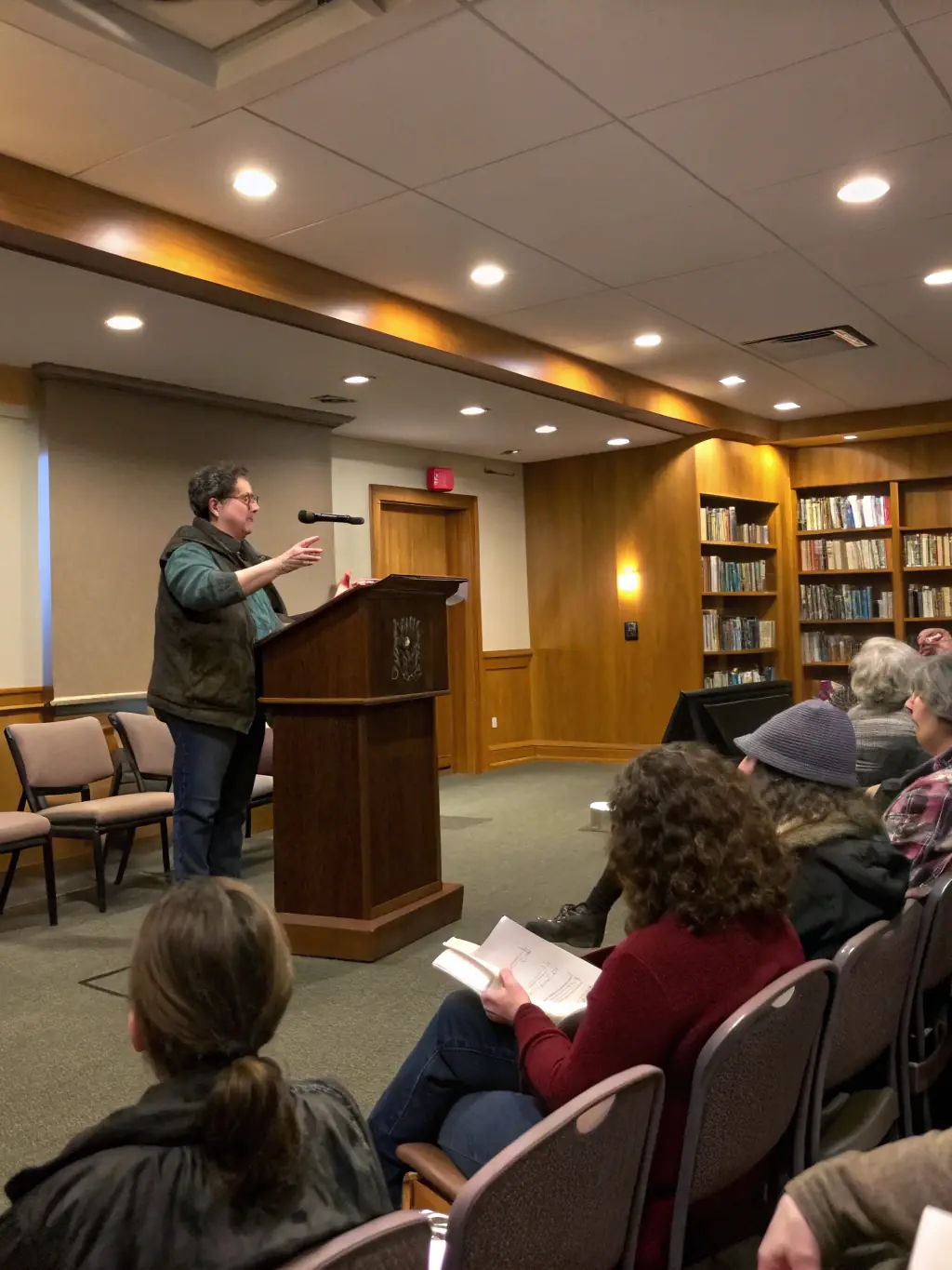 A photograph capturing a literary reading in a cozy setting, with attendees listening attentively to a speaker, showcasing the intimate and engaging atmosphere of the event.